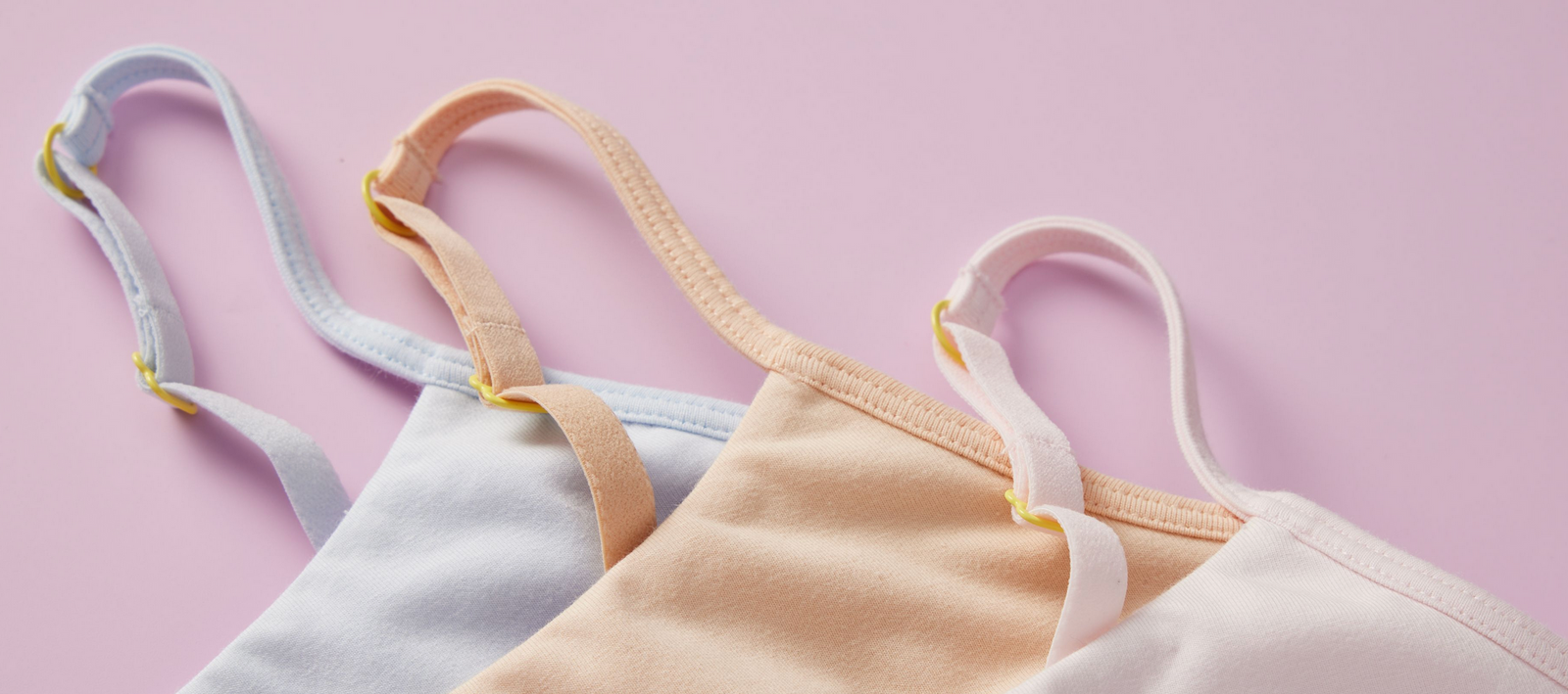 Three cotton Ladybug Bras by Yellowberry styled on a light pink background. They look soft and quality in the close-up image