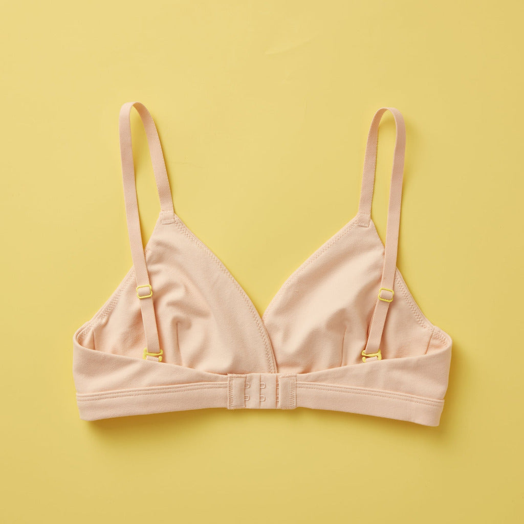 Yellowberry Butter Bra in beige, back laydown detail image. The BEST Bra We Make for More Developed Girls. Fabric is smooth to the touch and made with a matte brushed finish for extra softness. Made with synthetic fabric blend and hook and eye clasp closure. Great for developing girls. Wear and wash is over and over again, it will still look brand new. It will grow with your daughter as she continues to grow, great option for any occasion. Convertible straps. Adjustable straps.