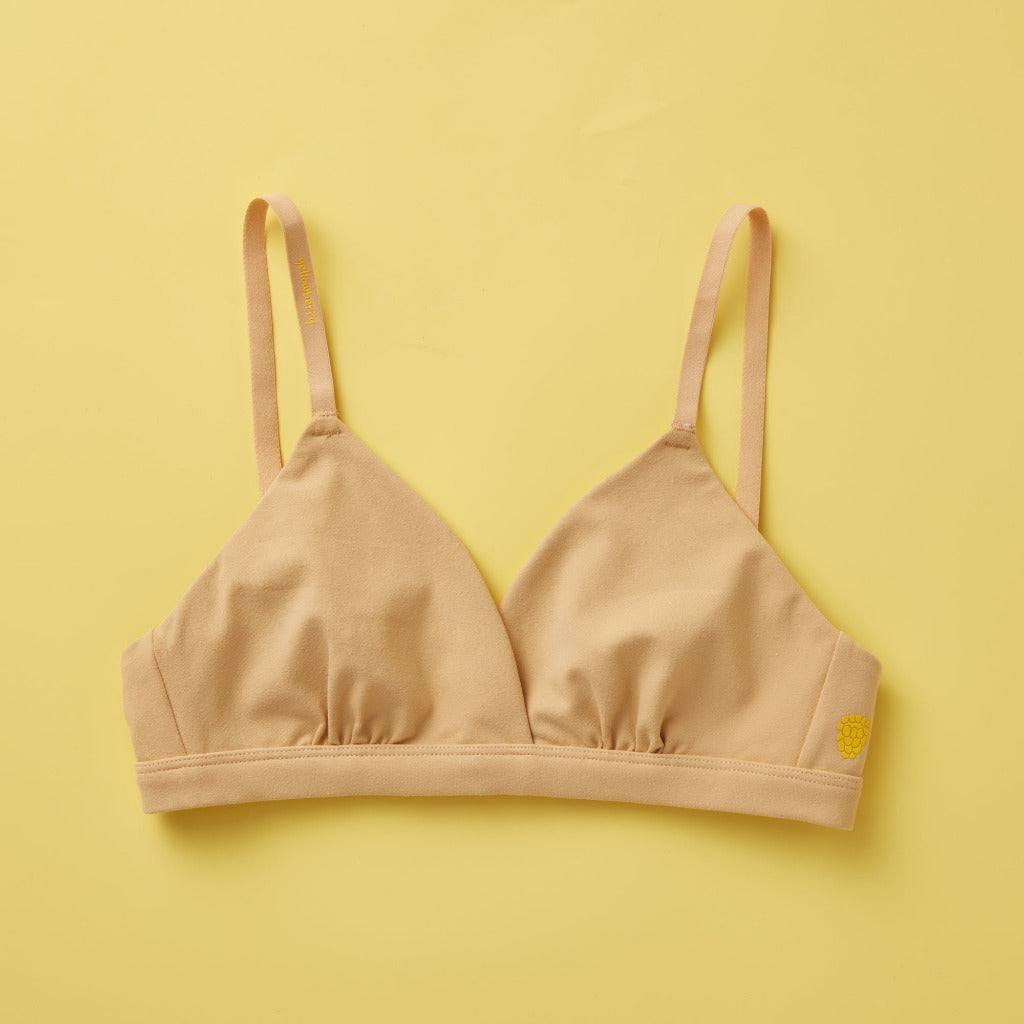 Yellowberry Butter Bra in coffee bean shade of nude color. Front laydown photo The BEST Bra We Make for More Developed Girls. Fabric is smooth to the touch and made with a matte brushed finish for extra softness. Made with synthetic fabric blend and hook and eye clasp closure. Great for developing girls. Wear and wash is over and over again, it will still look brand new. It will grow with your daughter as she continues to grow, great option for any occasion.