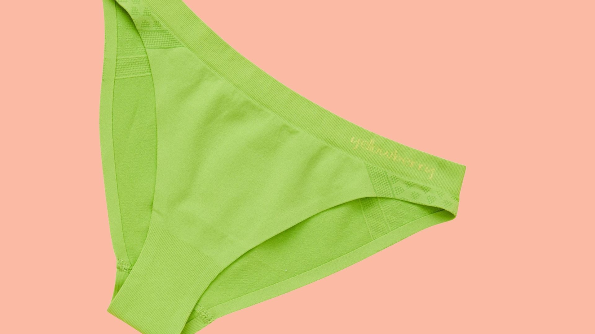 A pair of Yellowberry Scout Seamless Underwear in Lime Green on a peach colored background. 