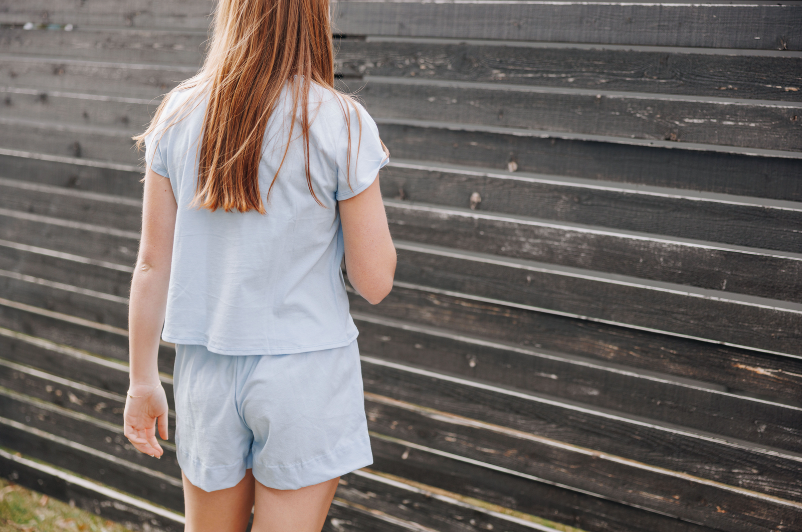 Girl facing away from the camera wearing a light blue cotton short sleeve t-shirt and matching light blue cotton shorts