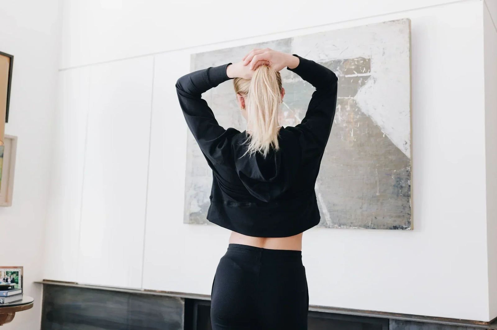 Girl putting her hair up in a ponytail. She is wearing a Yellowberry lounge set - a Downtown Hoodie and Uptown Jogger pants both in Starry Night color.