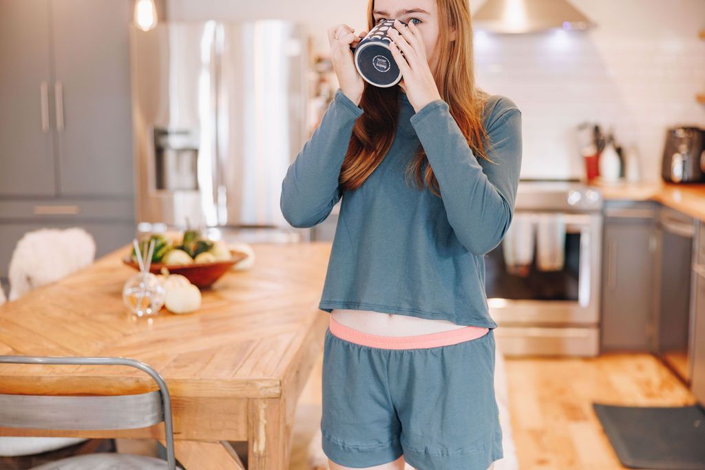 Girl sipping a hot drink in her kitchen wearing Yellowberry loungewear