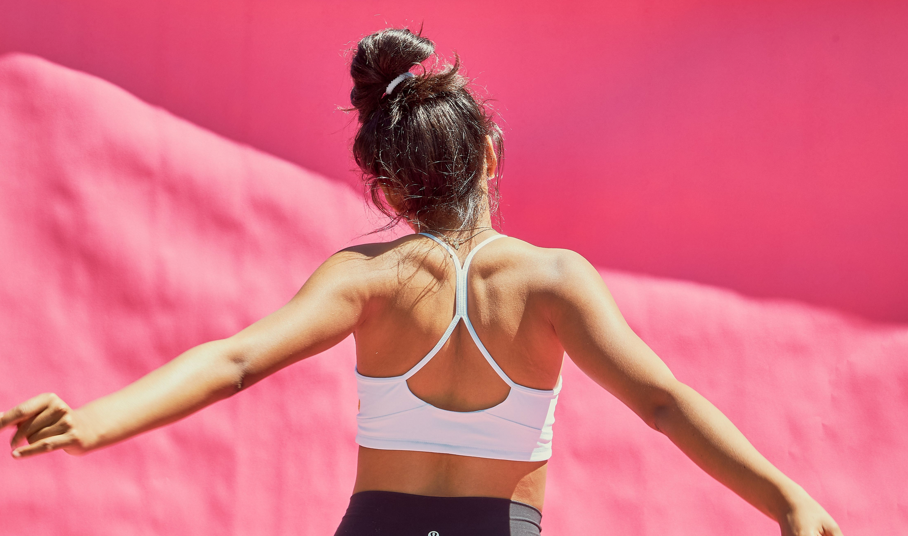 Girl dancing, facing a pink background away from the camera. She is wearing a Yellowberry Tink Snowflake color bra and snapping her fingers.