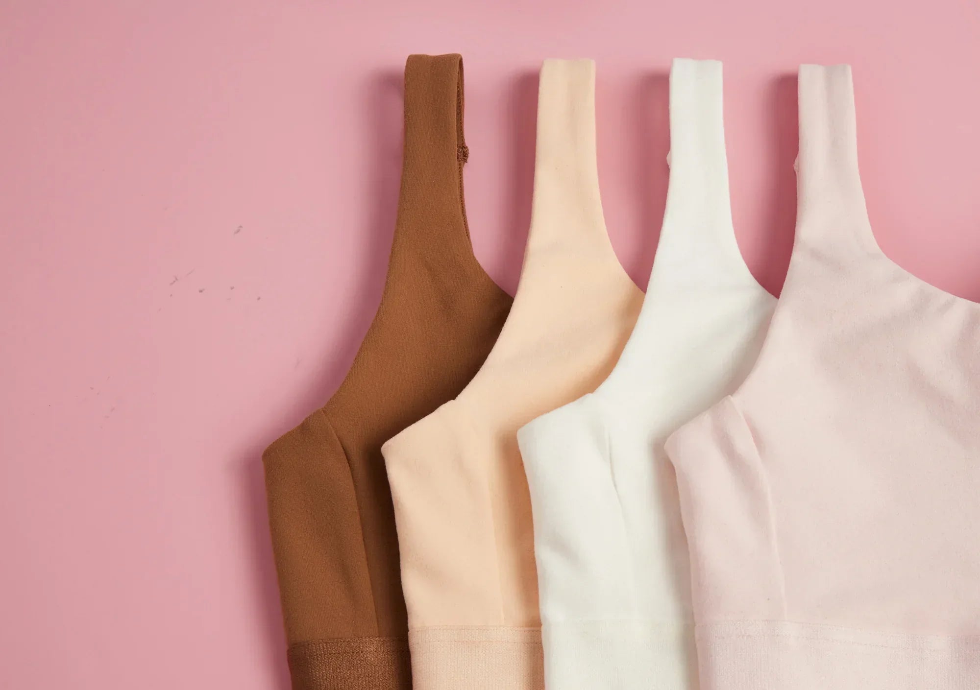 Four Yellowberry Bras in neutral colors on a pink background