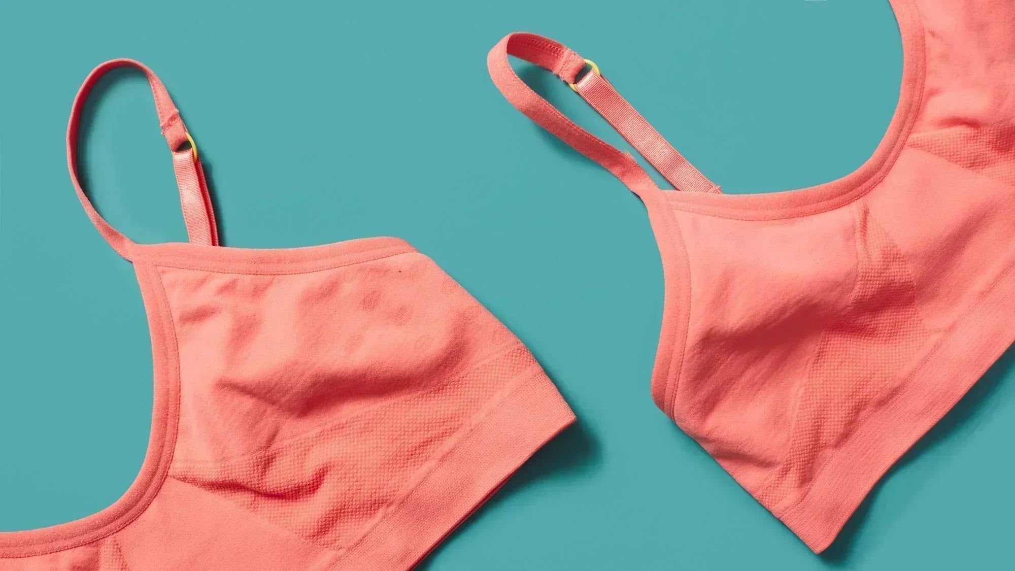 Two seamless Yellowberry bras laying on a teal background