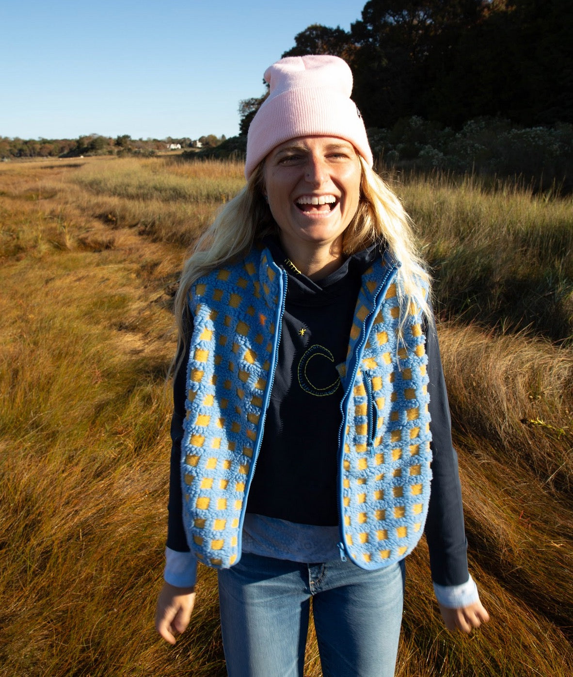 Girl laughing, wearing a hat and vest over along sleeve cotton girls  t-shirt