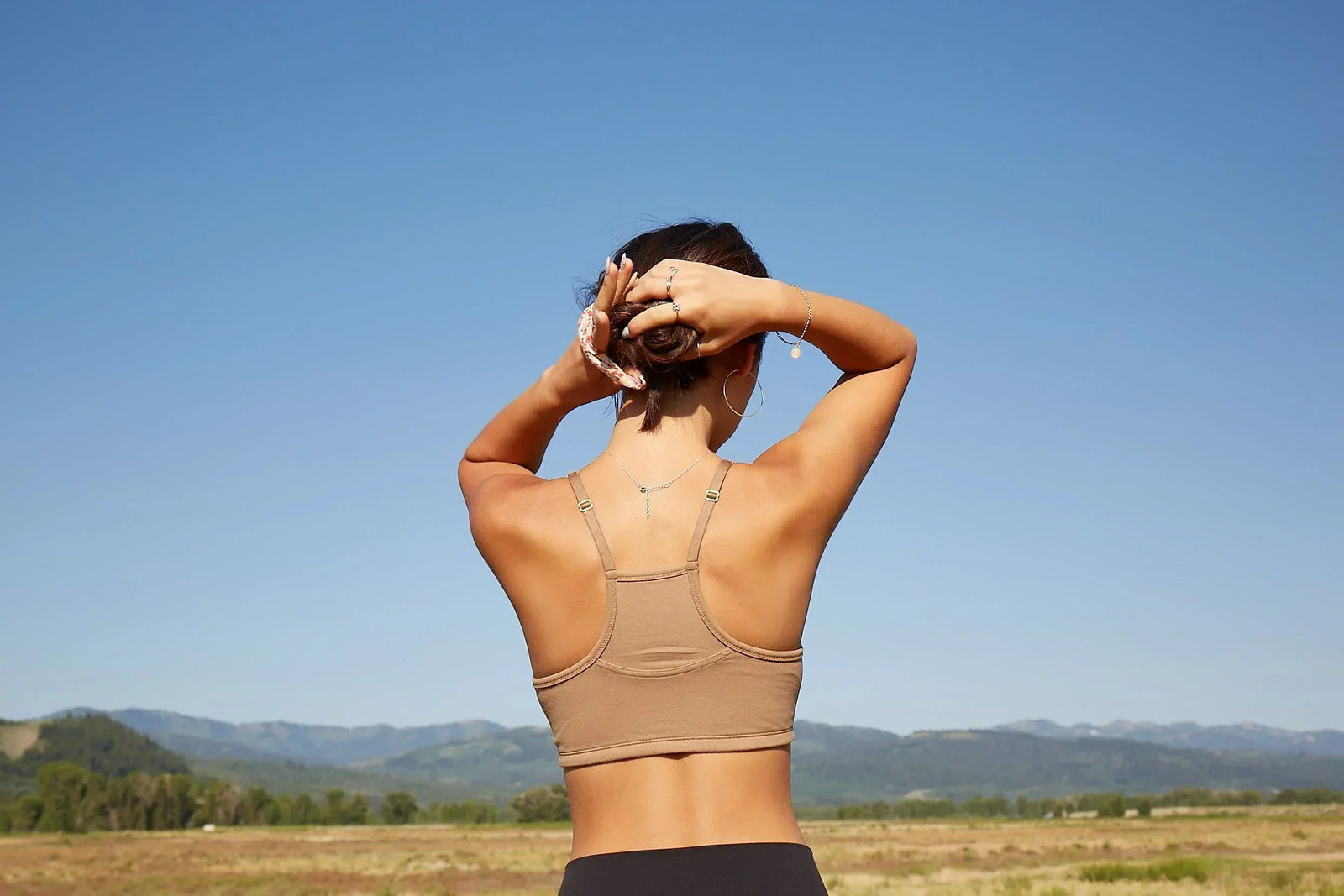 Girl wearing a Yellowberry Hybrid bra putting her hair in a ponytail