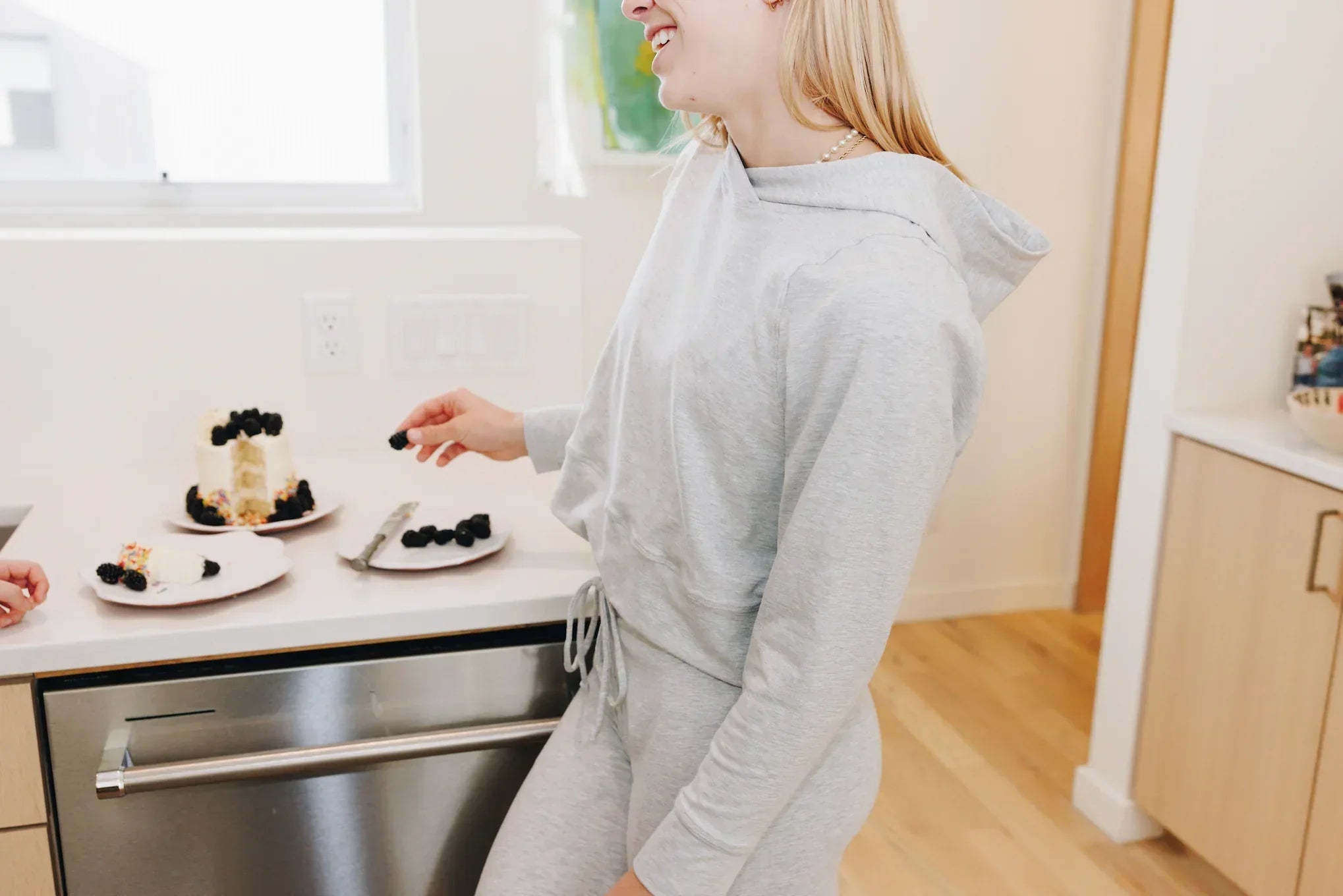 Girl standing at a counter in a Yellowberry matching set of grey downtown hoodie and grey uptown jogger pants.
