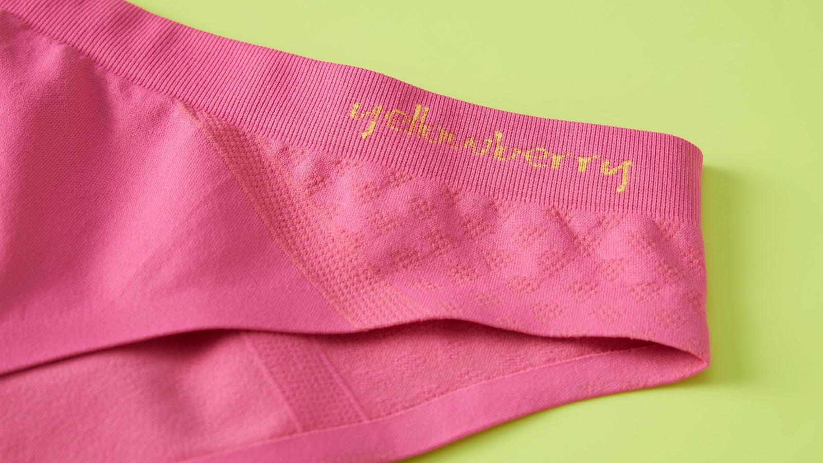 Watermelon pink colored Yellowberry seamless underwear displayed on a green background.