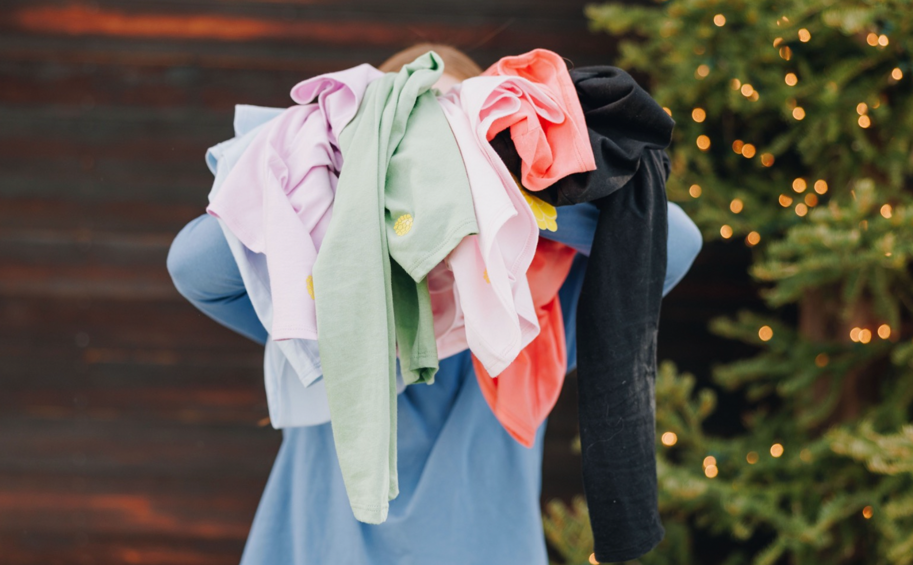Girl holding up several long sleeve cotton t-shirts