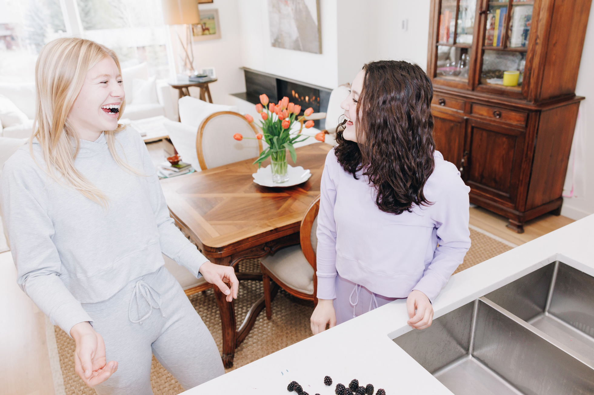 Two girls laughing. They are both wearing matching lounge sets. One is grey and the other is a light purple. The tops are Yellowberry downtown hoodies, and the bottoms are Yellowberry's uptown joggers.