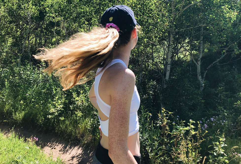 Girl on a hike, flipping her hair and wearing a white crop top