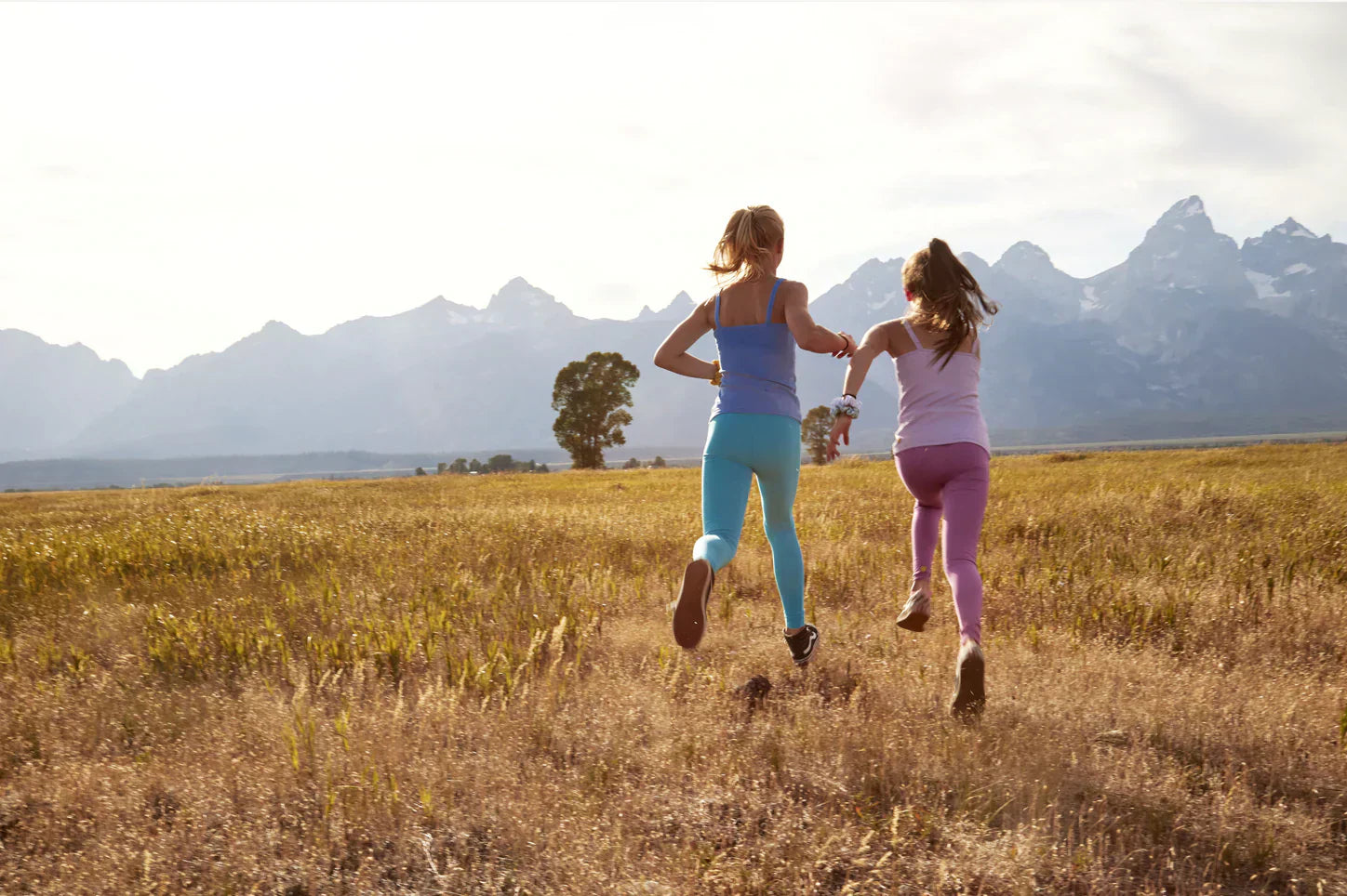 Two girls wearing head-to-toe Yellowberry are running towards a mountain