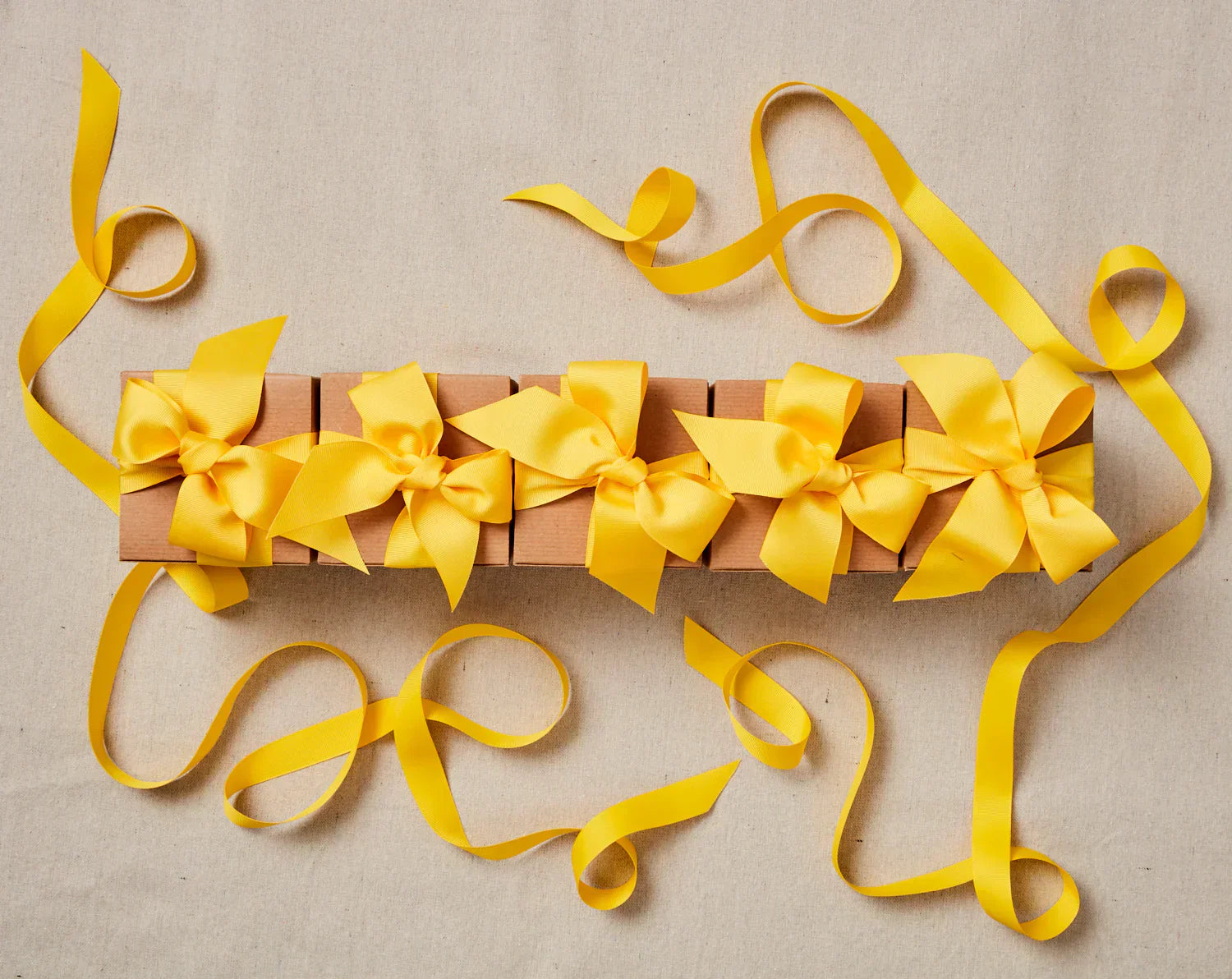 A series of Yellowberry Gift Boxes with yellow ribbon and bows are displayed in a line. They are well decorated with extra ribbon.