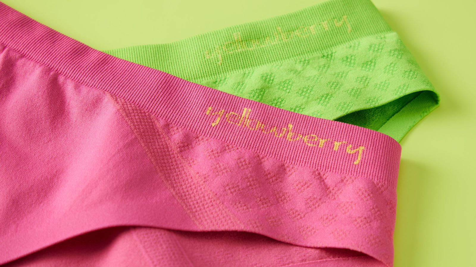 A pair of green yellowberry seamless underwear and a pair of watermelon pink yellowberry seamless underwear styled on top of a green background
