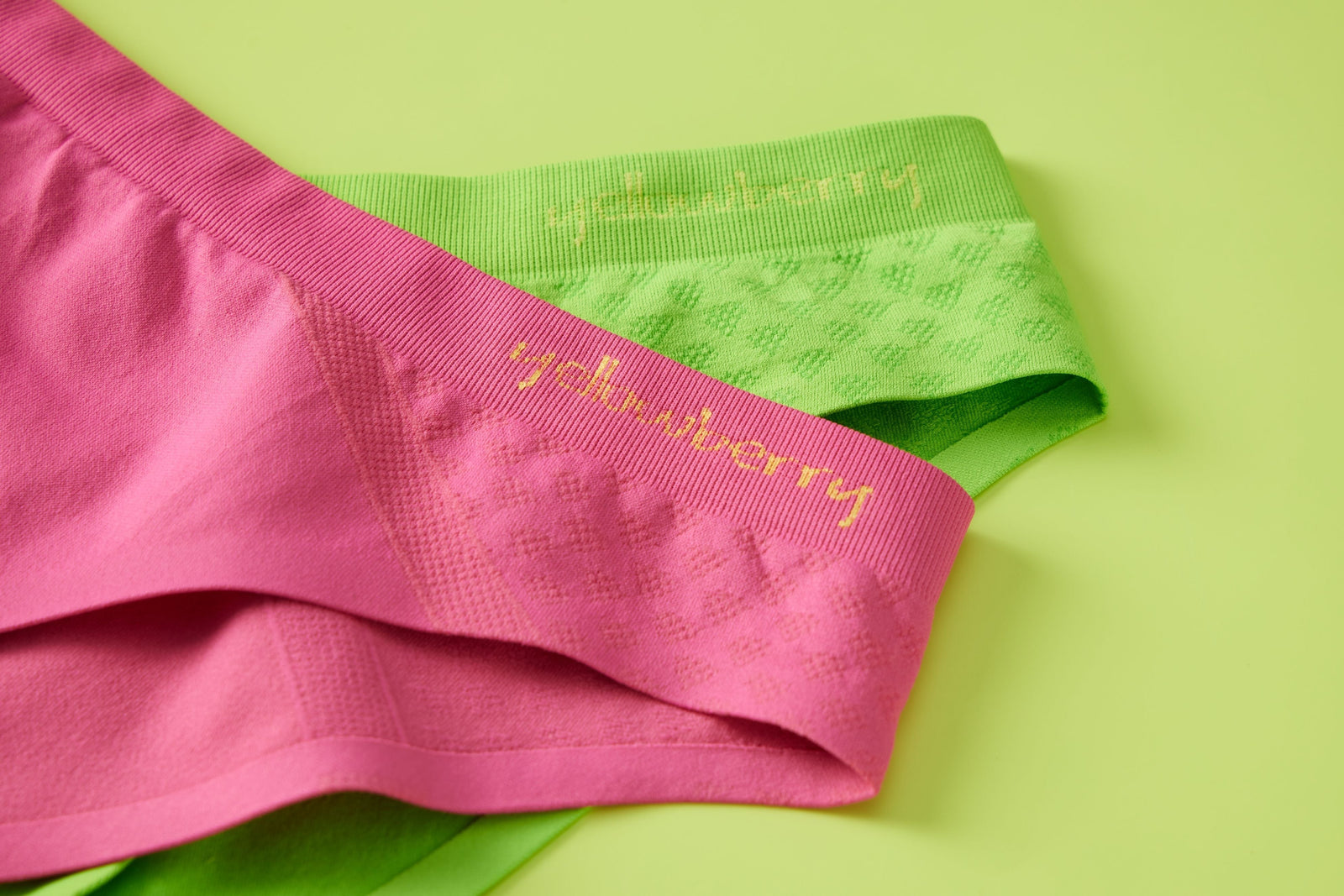 A pair of green yellowberry seamless underwear and a pair of watermelon pink yellowberry seamless underwear styled on top of a green background