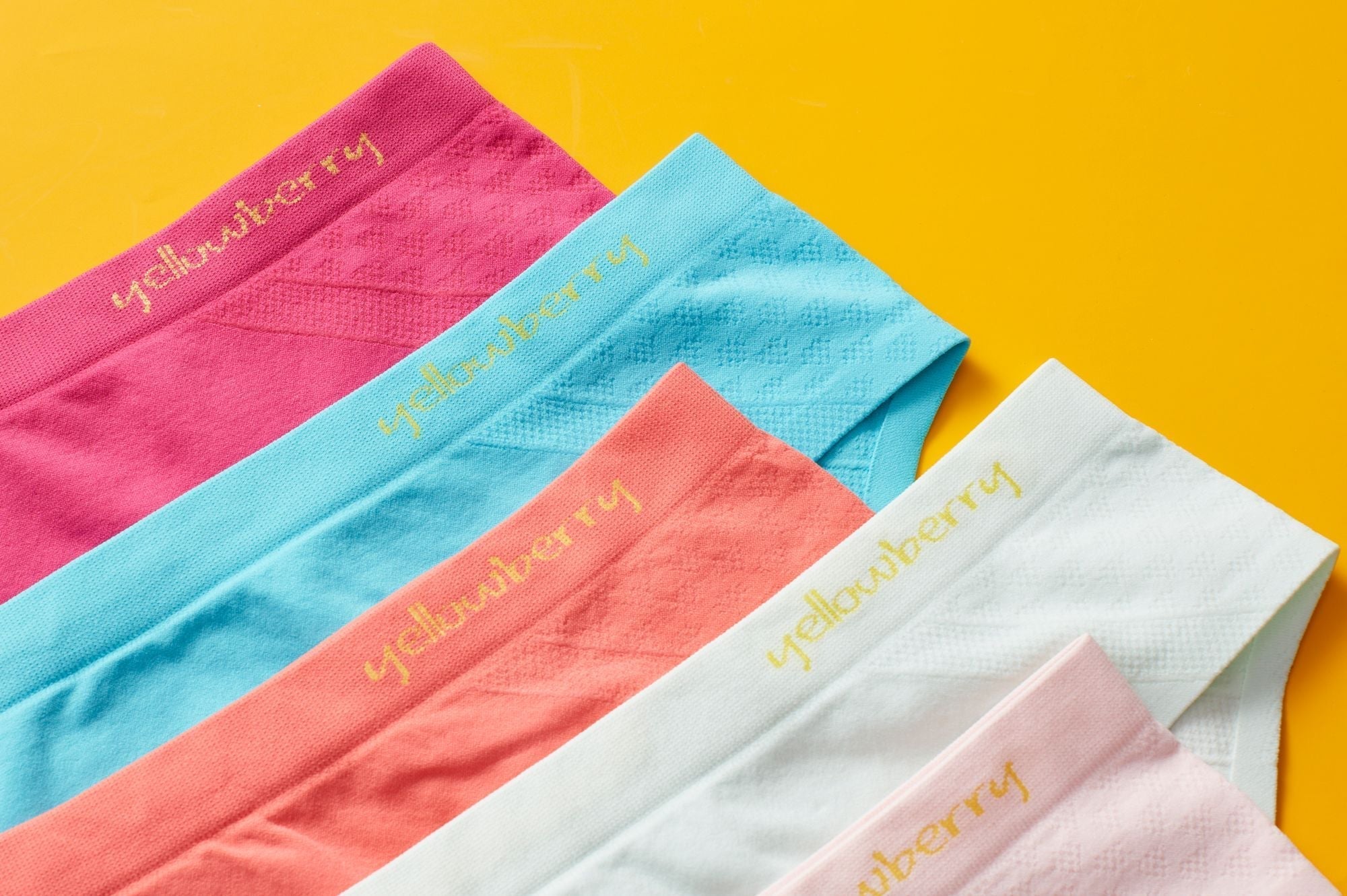 Multiple pairs of colorful seamless girls underwear styled on a yellow background