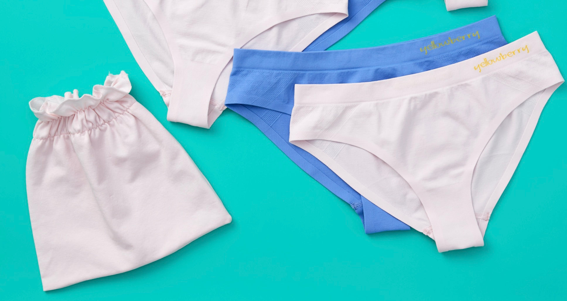 A bright turquoise background with several pair of Yellowberry underwear styled on top next to a fabric packaging bag.