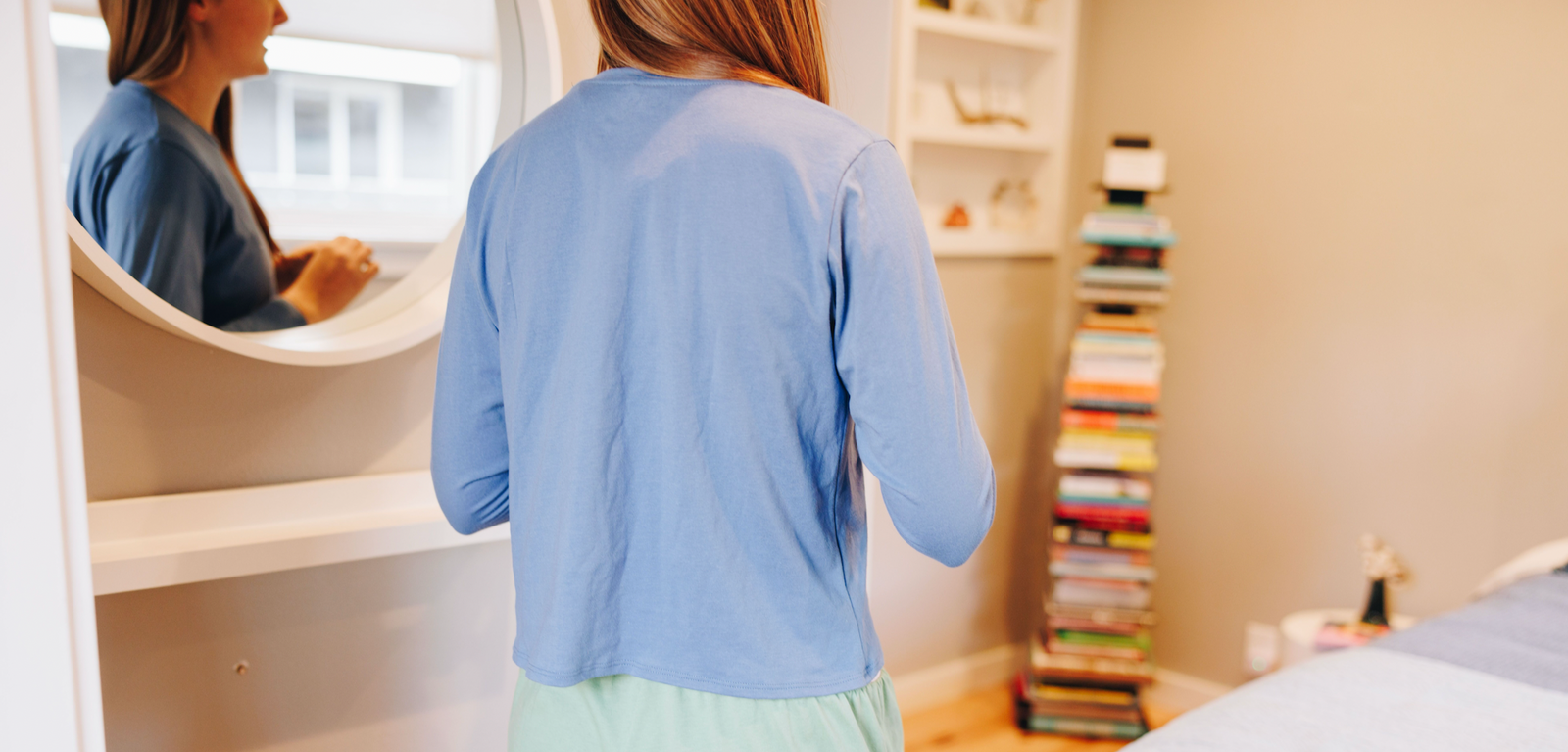 Girl standing in front of a mirror wearing an ocean blue long sleeve cotton t-shirt