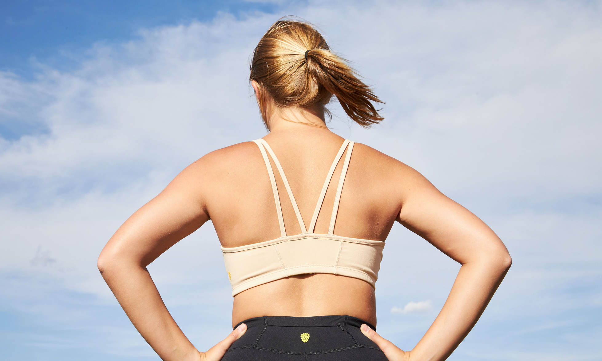 A girl with her hands on her hips in a beige yellowberry hybrid sports bra