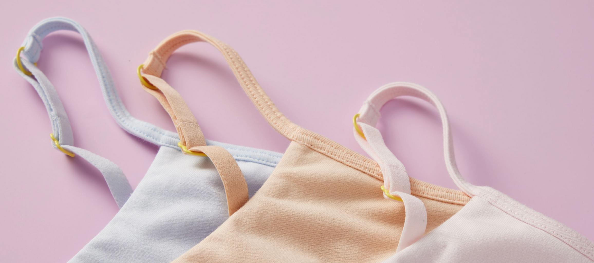 Three cotton Ladybug Bras by Yellowberry styled on a light pink background. They look soft and quality in the close-up image