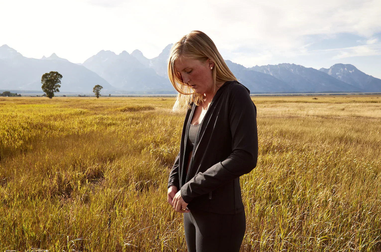 Girl standing in a field zipping up her Yellowberry jacket