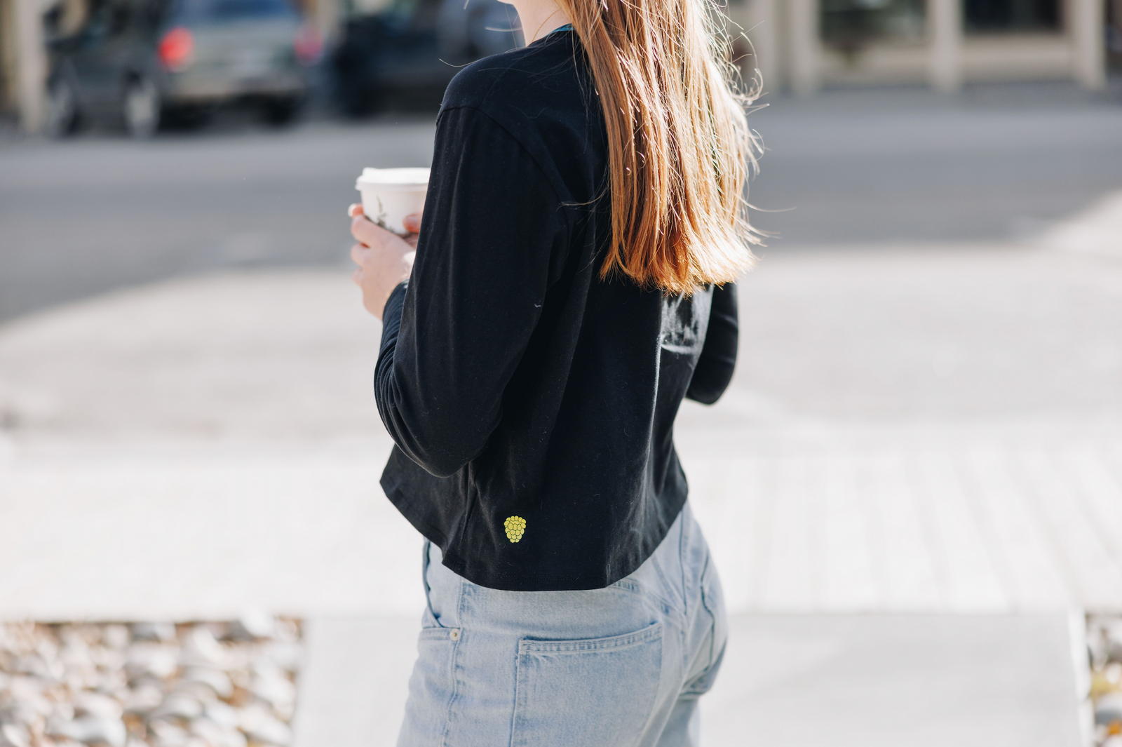 Girl standing, holding coffee wearing a long-sleeve cotton t-shirt from Yellowberry