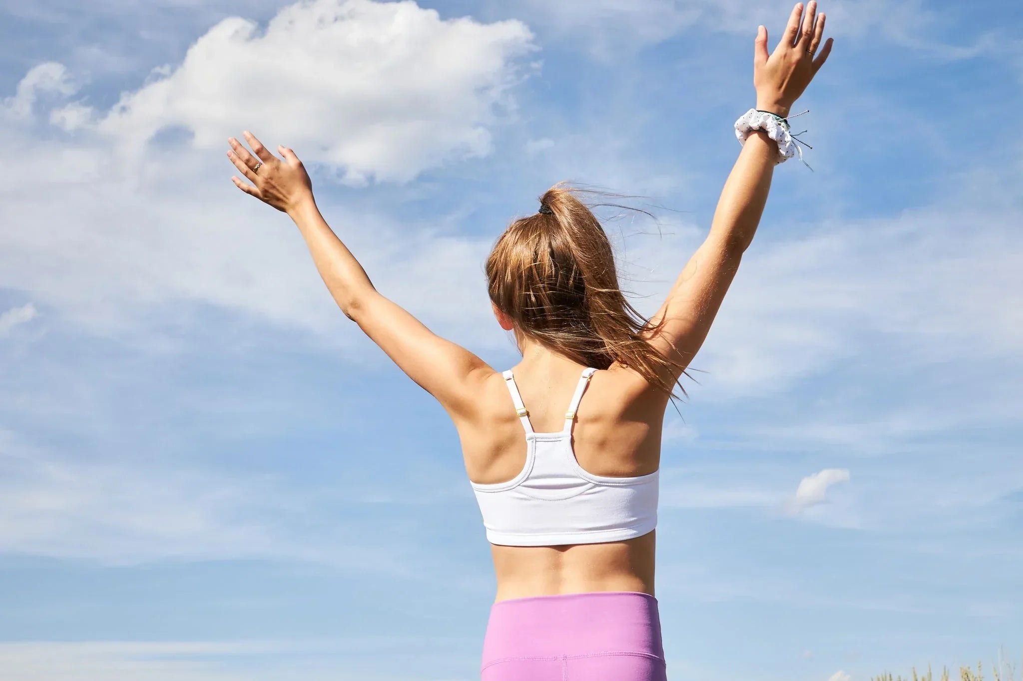 Girl standing with her arms in the air against the sky wearing a Yellowberry Bra for Small Breasts