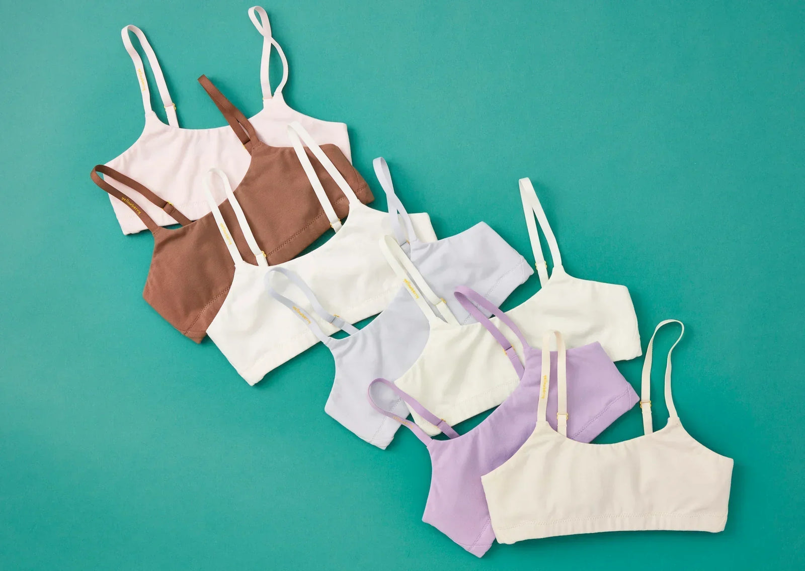 A series of multiple colored Yellowberry Bras arranged on a turquoise background