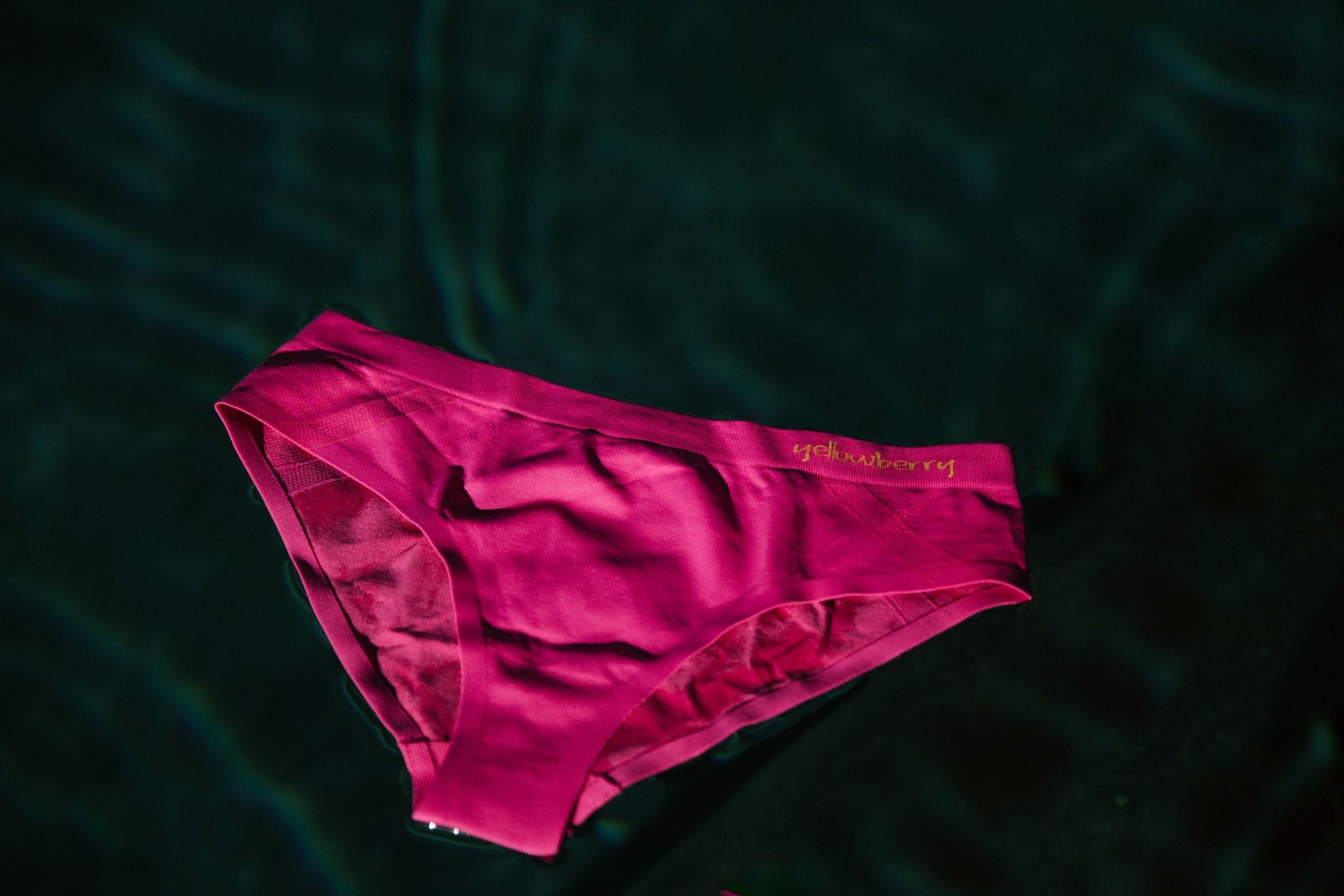 A pair of Yellowberry watermelon pink seamless underwear floating in water.