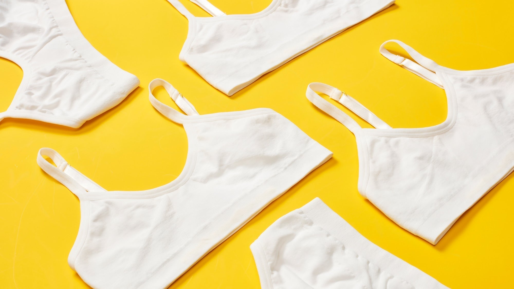 Several White Yellowberry Seamless Bras are styled on a yellow background