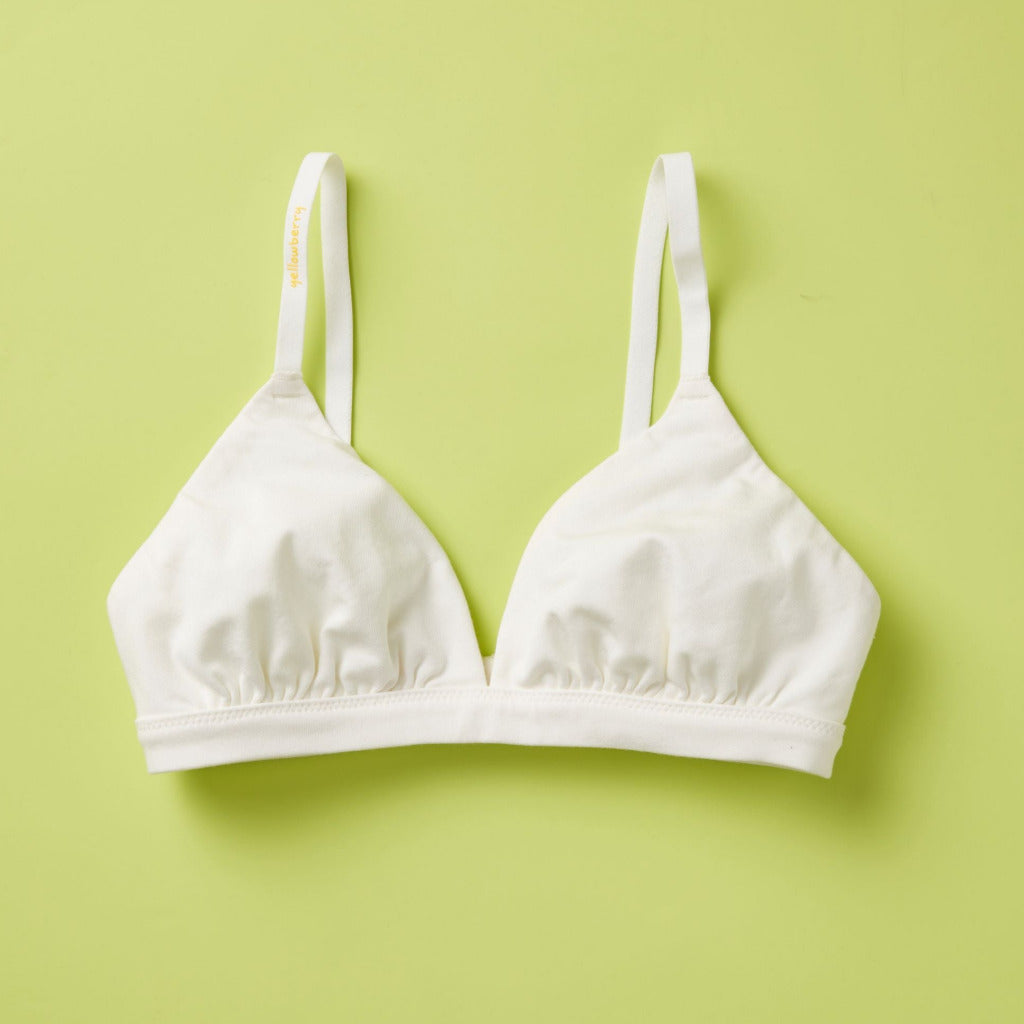 White Joey Bra by Yellowberry, styled on a light green background