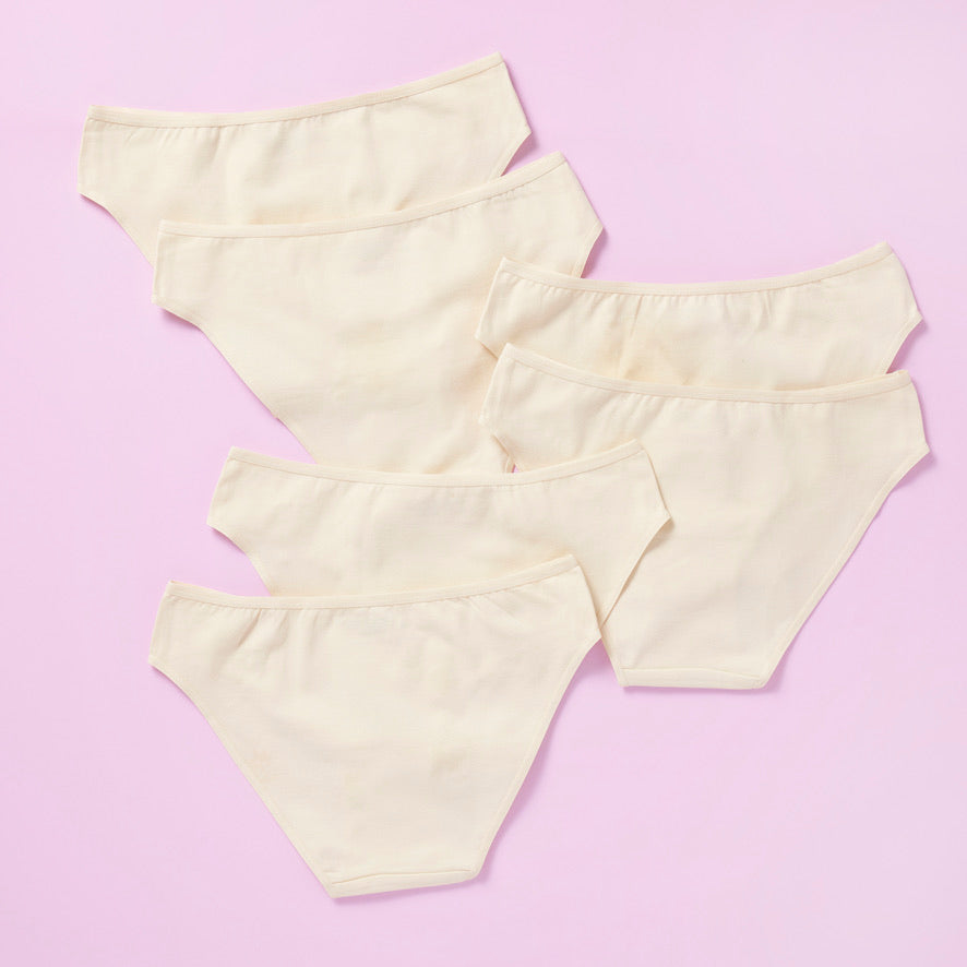 6 pair of beige girls cotton bikini cut underwear on a pretty pink background, back