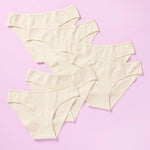 6 pair of beige girls cotton bikini cut underwear on a pretty pink background, front