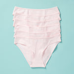 6 pair of light pink girls cotton bikini cut underwear assembled on an aqua background, front