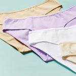 close up image of different colored cotton bikini cut underwear assembled on an aqua background, front