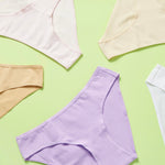 5 different colored cotton bikini cut underwear assembled in a loose wheel on a green background, front