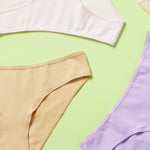 close up of different colored cotton bikini cut underwear assembled in a loose wheel on a green background, front