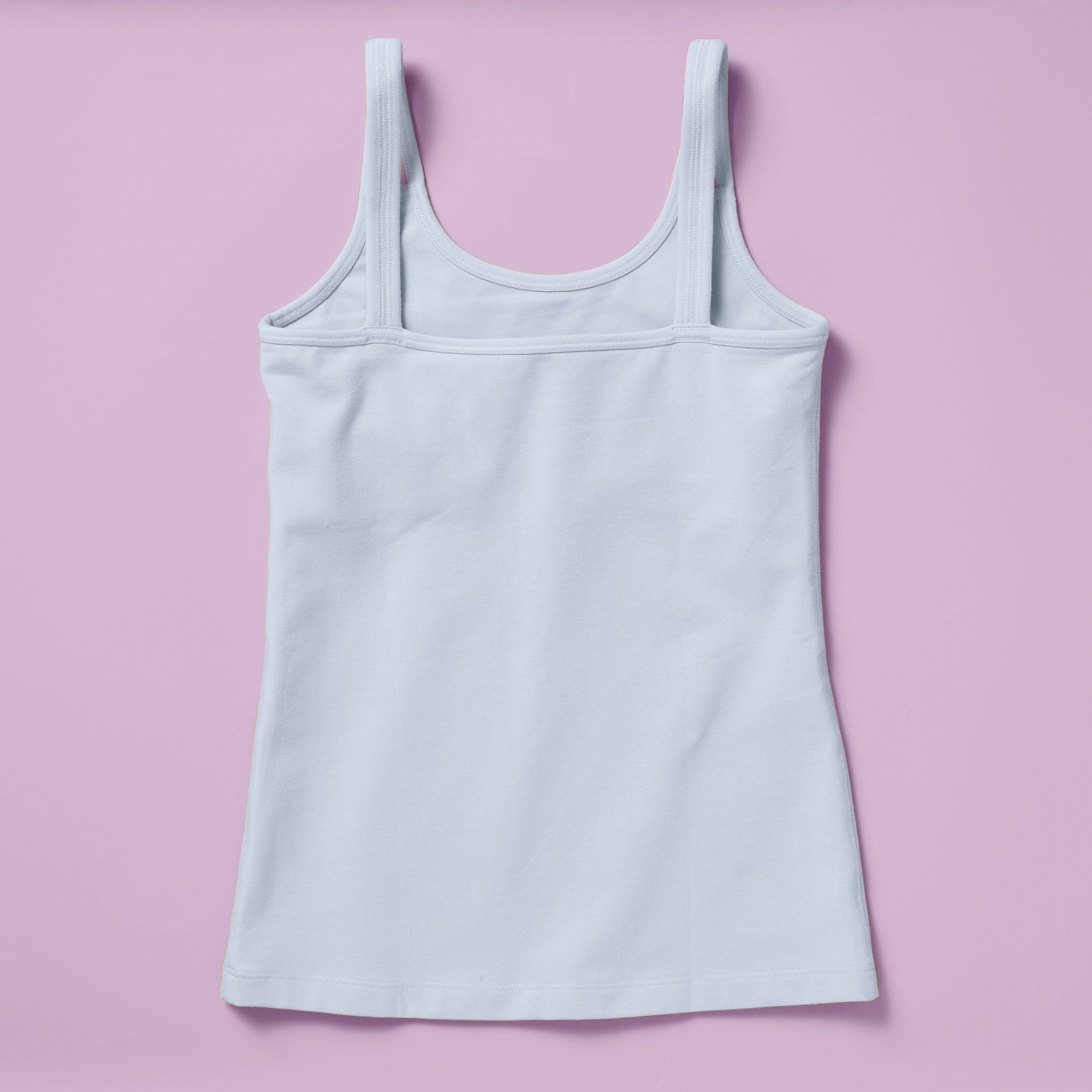 Laydown image of the back of a light blue cotton camisole with a shelf bra on a light purple background