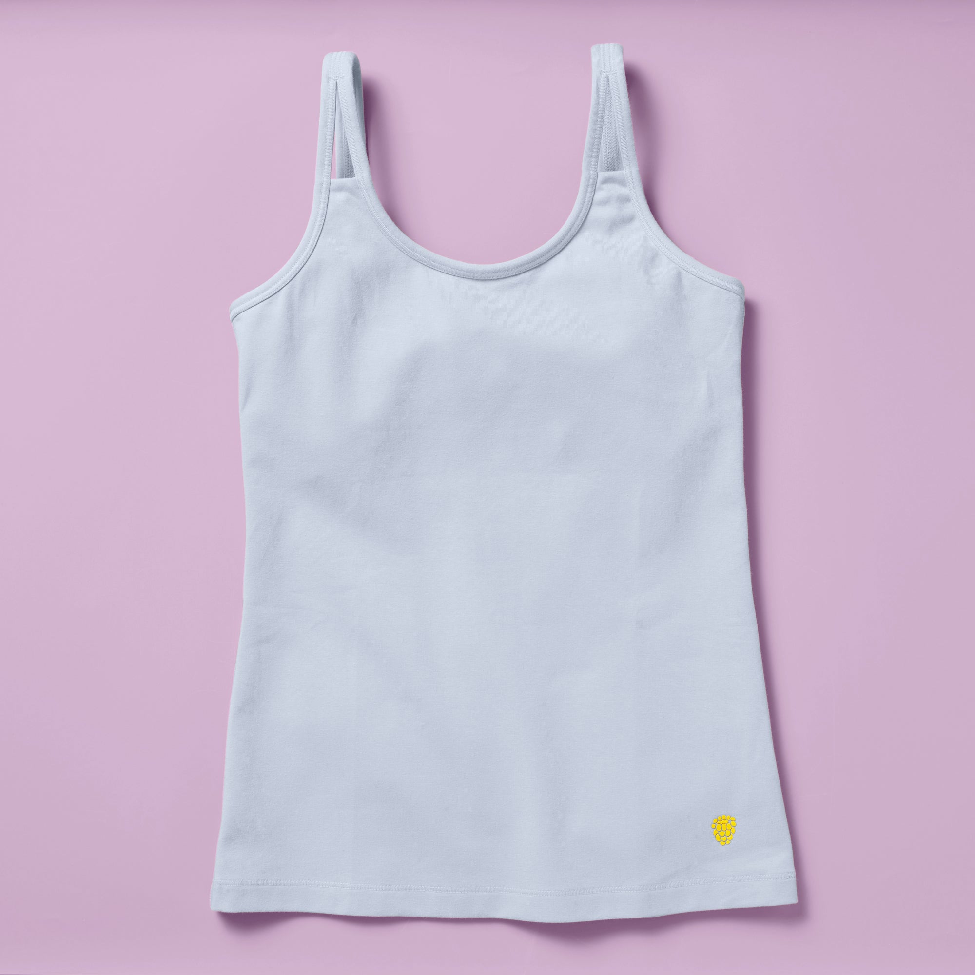 Laydown image of the front of a light blue cotton camisole with a shelf bra on a light purple background
