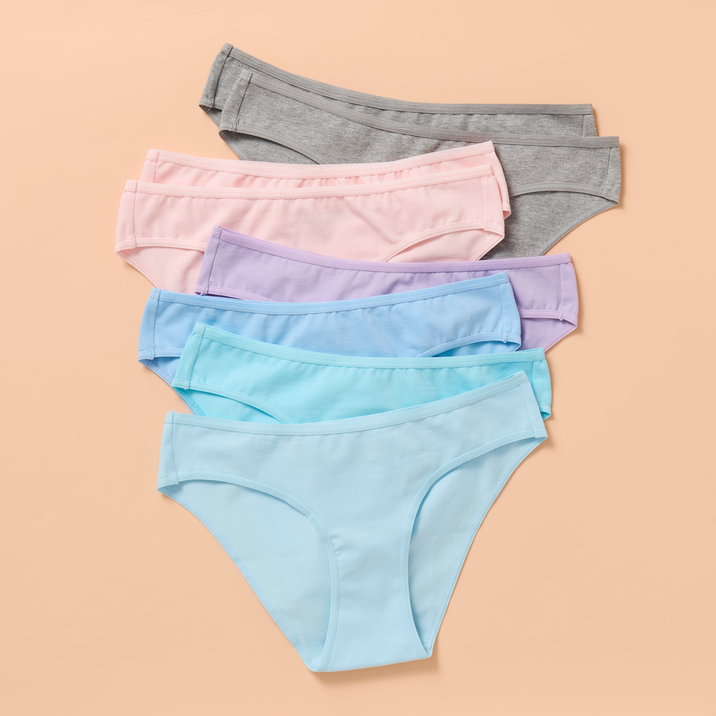 Set of pastel-colored underwear on a beige background