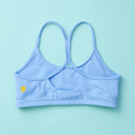 Tink Sports Bra by Yellowberry in a soft brushed nylon blend in Ocean Blue. A Classic pullover design with full support ensures all-day ease and comfort. Ocean is a great new blue with a hint of turquoise. Lay down image of Back Tink Ocean against a turquoise background.