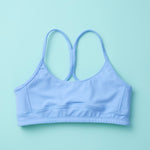 Tink Sports Bra by Yellowberry in a soft brushed nylon blend in Ocean Blue. A Classic pullover design with full support ensures all-day ease and comfort. Ocean is a great new blue with a hint of turquoise. Lay down image of Front Tink Ocean against a turquoise background.