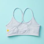 Tink Sports Bra by Yellowberry in a soft brushed nylon blend in a super mild grey, Storm. A Classicly designed bra with full support that ensures all-day ease and comfort. Our Storm colorway is a great neutral. Laydown image of BackTink Storm against a turquoise background.