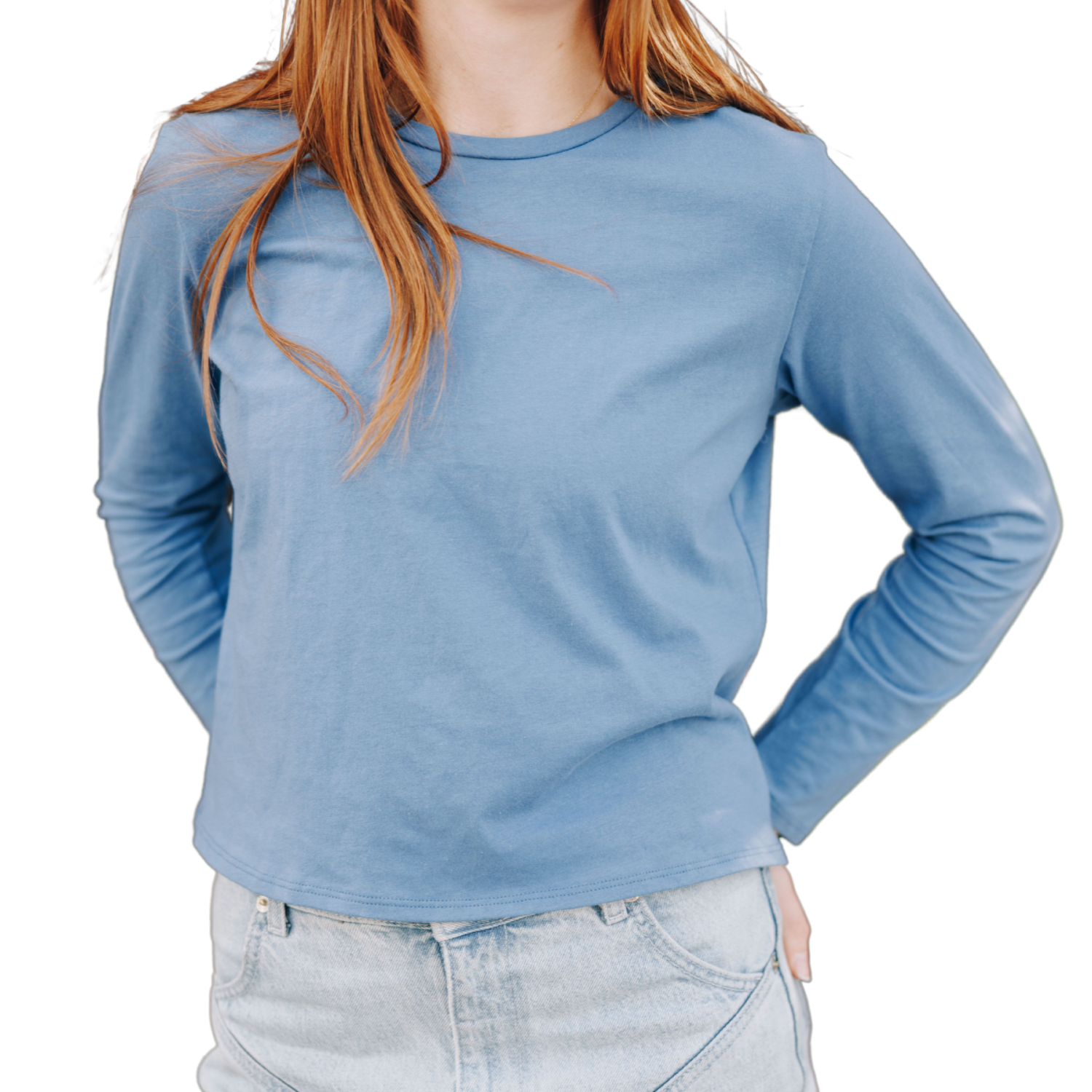 Girl wearing an ocean blue colored long sleeve cotton t-shirt, has her hands behind her hips and her strawberry blonde hair over her shoulder