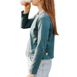 Girl Girl wearing a blue green long sleeved cotton t-shirt drinking a hot drink