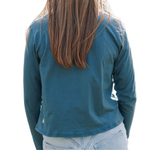 Girl wearing a blue green long sleeved cotton t-shirt from the back with strawberry blonde hair 