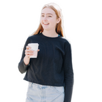 Girl smiling and wearing long sleeve black cotton whisper t-shirt holding a coffee and wearing jeans