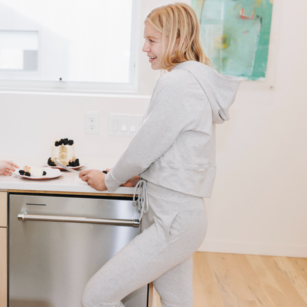 Yellowberry Downtown Hoodie in soft cotton, and effortless Style. Designed with a cross-front hood for subtle flair, it falls just below the navel, hitting the hip for a relaxed, effortless fit. Each piece in our lounge collection embodies chic, timeless style, all essentials you'll reach for all cozy season long. Made with pride in the USA, in colors thoughtfully chosen to mix and match seamlessly. We hope you enjoy them as much as we loved creating them for you. Morning Mist side on model with cake